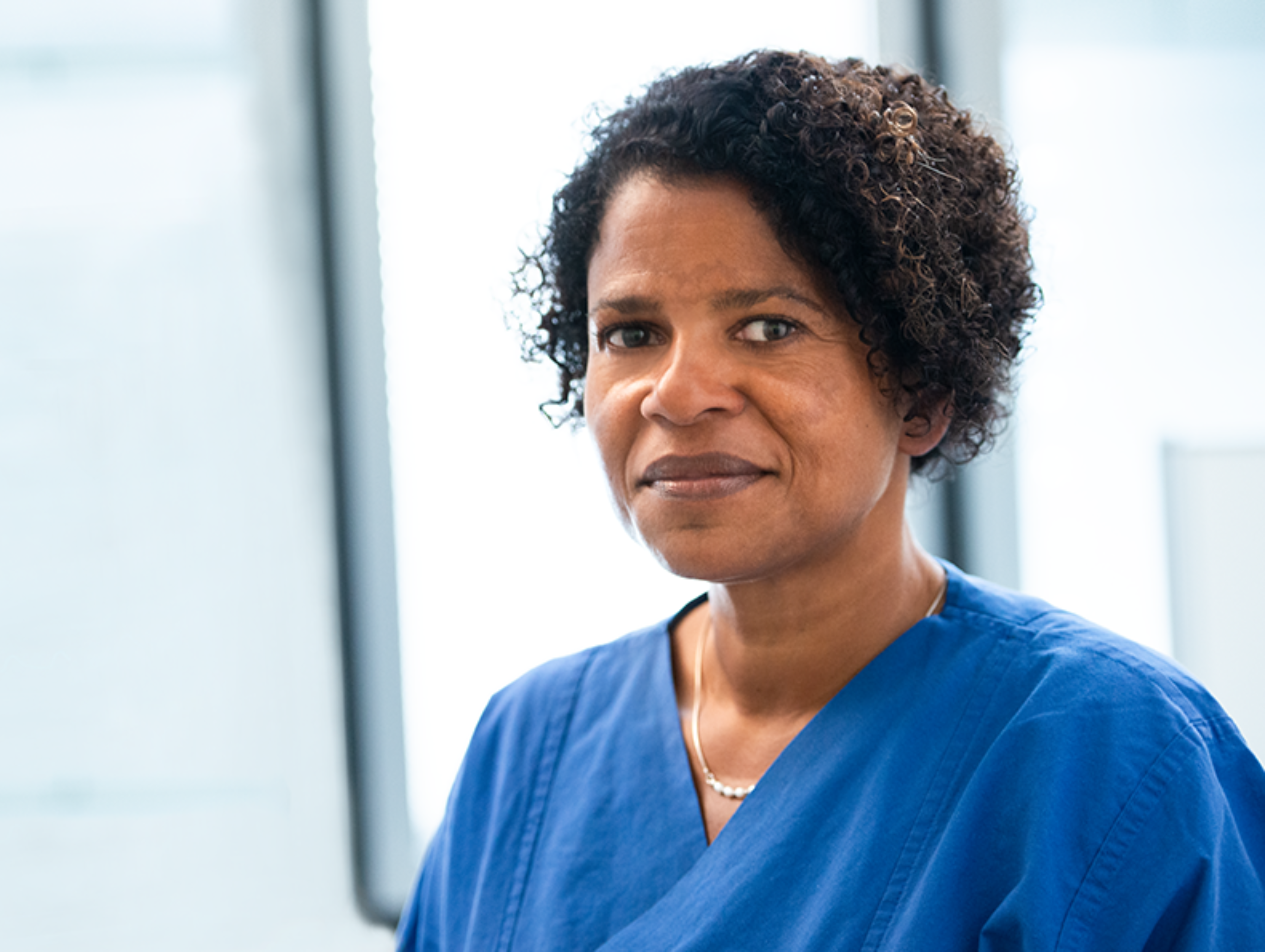 BZgA Organspende Blog Interview Dr. Geraldine de Heer 1 Das Foto ist eine Porträtaufnahme von Dr. Geraldine de Heer. Sie trägt medizinische Kleidung und lächelt in die Kamera.
