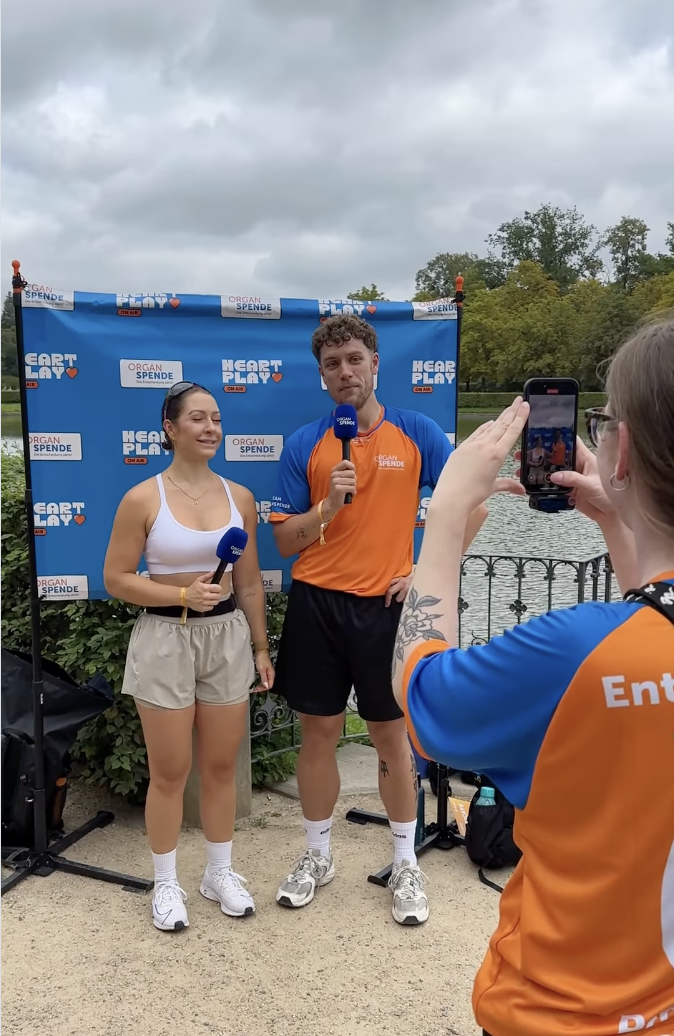 Das Bild zeigt eine Läuferin und Smitty bei einem Interview und eine Person, die die beiden filmt.