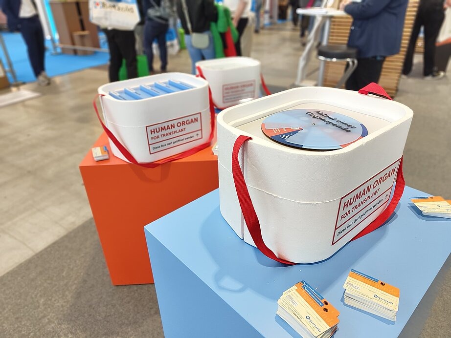 Das Bild zeigt eine Organspende-Box auf einem Tisch des Messestandes. Sie symbolisiert eine reale Box, in welche Organe von A nach B transportiert werden.