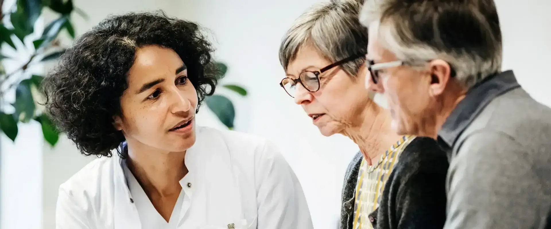Zwei ältere Menschen, eine Frau und ein Mann, lassen sich von einer Ärztin beraten.