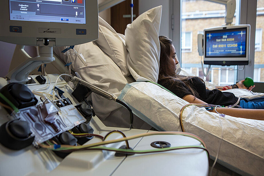Zu sehen ist eine junge Frau, die im Bett liegt, während eine Stammzellenspende durchgeführt wird.